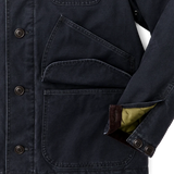 Close up of bottom right of navy jacket. There are three dark buttons on the left side. The sleeve is unbuttoned to show tan lining and dark brown corduroy around the interior of the sleeve opening. The flap of the cargo pocket is pulled open.