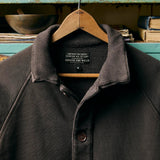 Close up of cotton terry raglan sleeve shirt with turnback hem sleeves and ribbed collar on hanger.