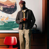 Man wearing a cotton terry raglan sleeve shirt with turnback hem sleeves and ribbed collar, a beanie, and holding a red mug.