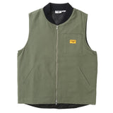 Front of an olive green canvas vest with a silver colored zipper down the center, black knit ribbing around the collar, two hand-warmer style pockets, and a chest pocket on the wearer's left side. Over the chest pocket is a small orange fabric patch with the Service Works logo. 