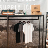 3 Blank Tees in Black, White and Grey Hanging from a Rack.
