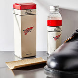 Foam leather cleaner in a glass bottle next to a pair of leather boots